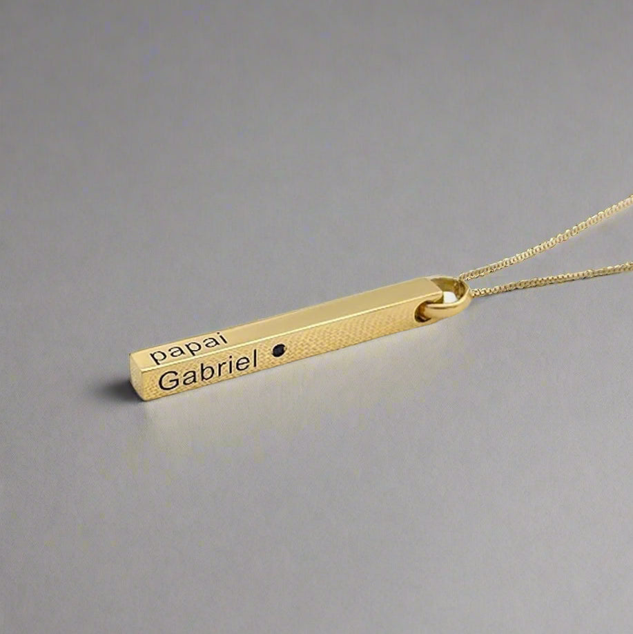 Gold necklace with engraved pendant on a light gray background