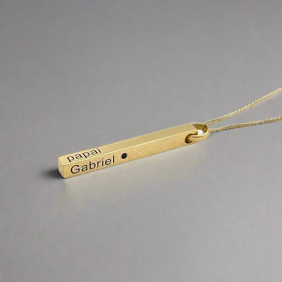 Gold necklace with engraved pendant on a light gray background