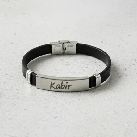 Black rubber and silver metal bracelet with 'Kabir' engraving on a light gray surface