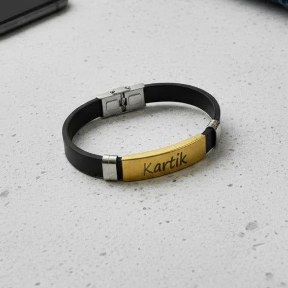 Black and gold bracelet with 'Kartik' engraving on a gray surface