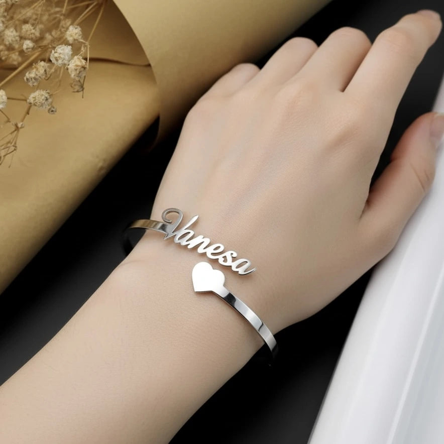 Silver bracelet with 'Vanesa' on a wrist against a dark background
