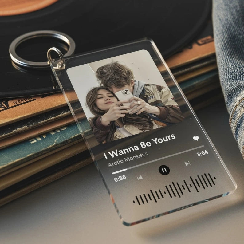 Clear keychain with music player design featuring a couple and song details, placed on vinyl records.
