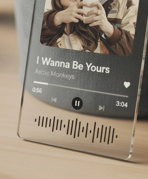 Music player display with 'I Wanna Be Yours' by Arctic Monkeys on a clear stand.