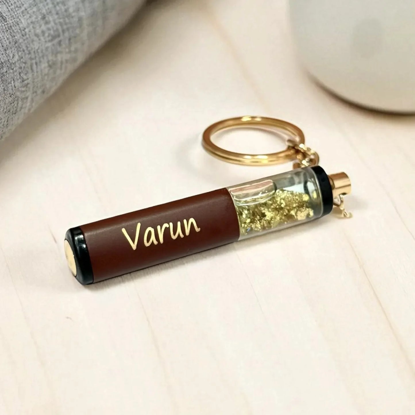 Keychain with a cylindrical container labeled 'Varun' on a light surface.