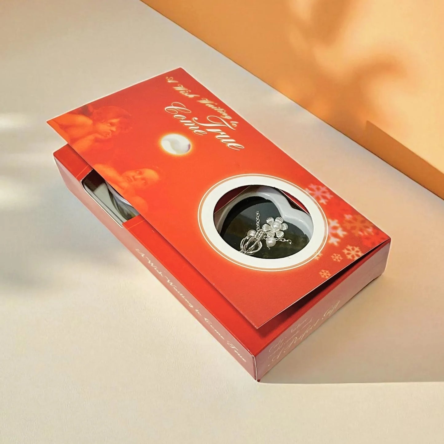 Red jewelry box with a silver ring inside on a beige surface