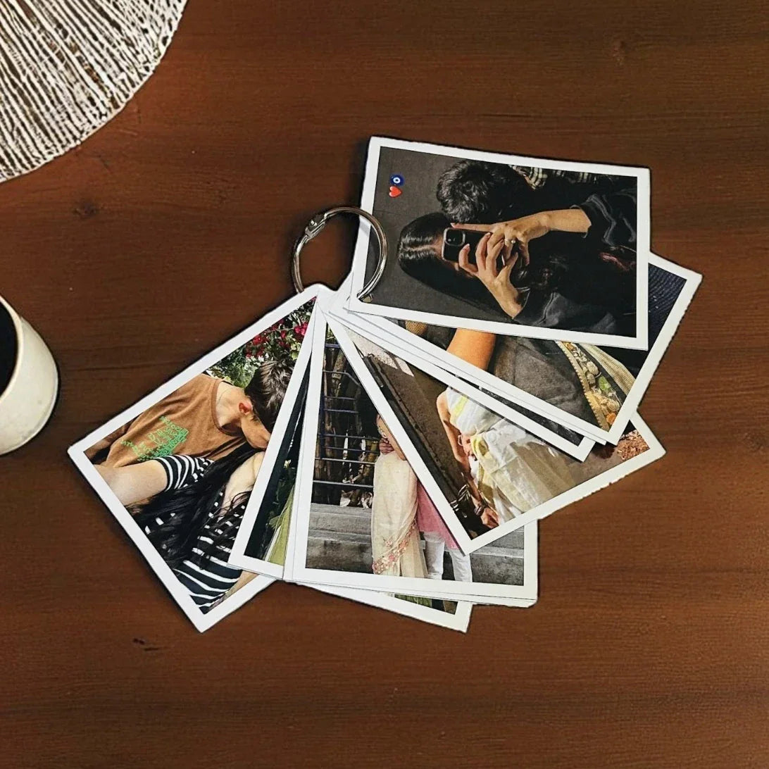Stack of photo prints on a wooden surface with a coffee cup in the corner.