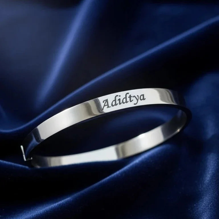 Silver bracelet with engraved name on a blue satin background