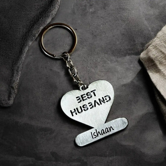 Heart-shaped keychain with 'Best Husband Ishaan' text on a dark surface