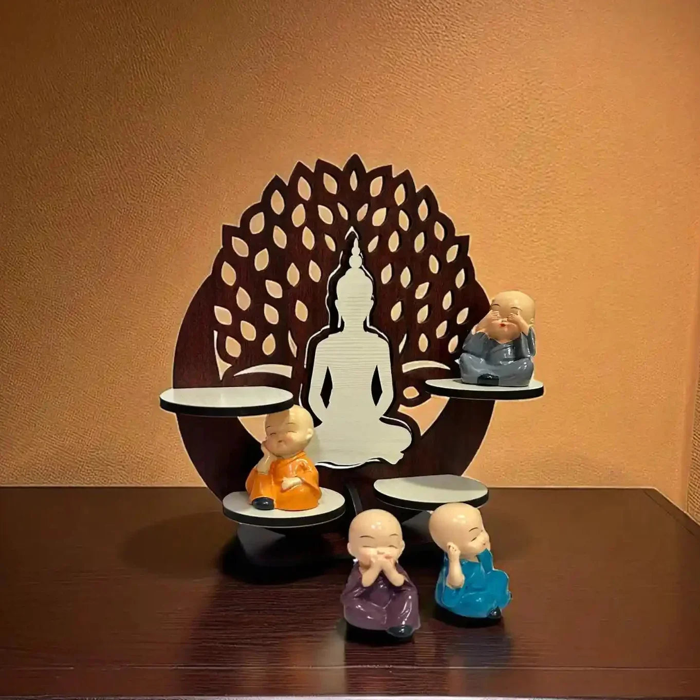 Decorative set with Buddha statues on a wooden shelf against a brown wall.