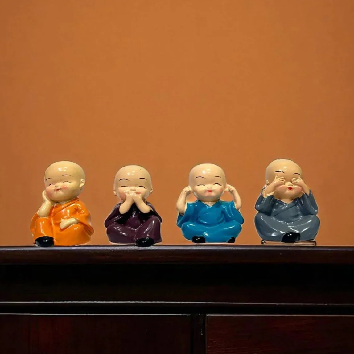 Four small figurines on a wooden surface with an orange background