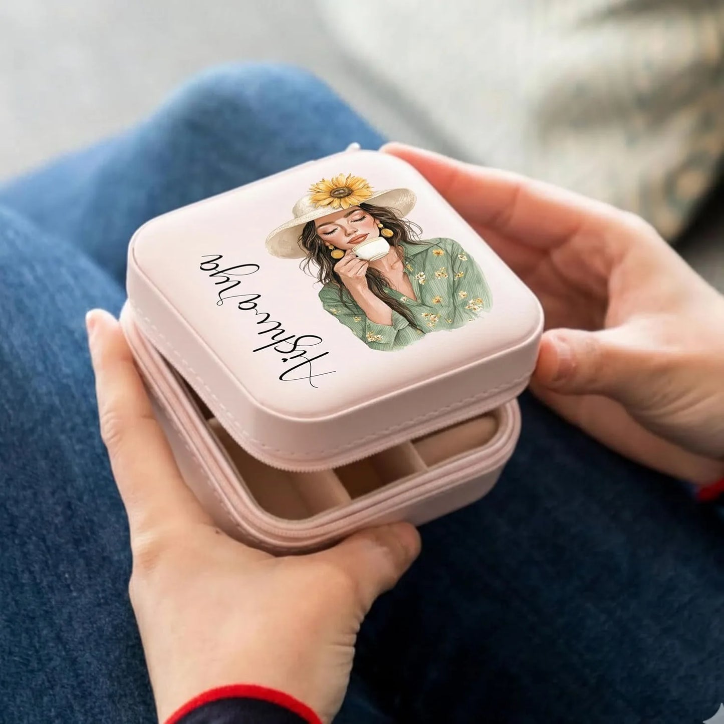 Person holding a pink compact mirror with a design on the lid