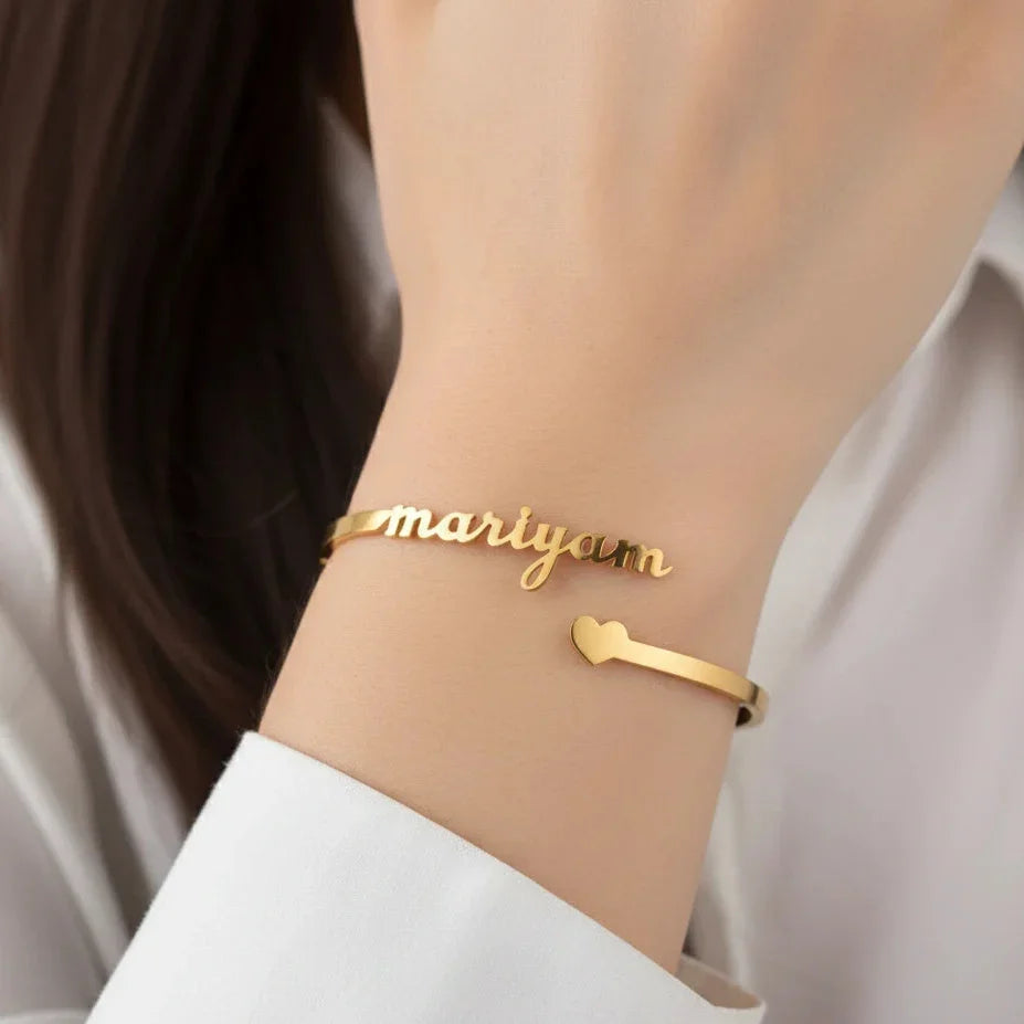 Gold bracelet with 'maryam' on a wrist against a neutral background