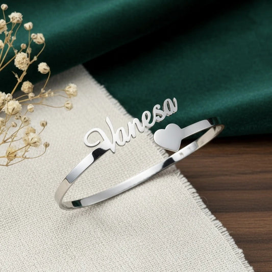 Silver bracelet with 'Vanessa' engraving on a textured surface with dried flowers.
