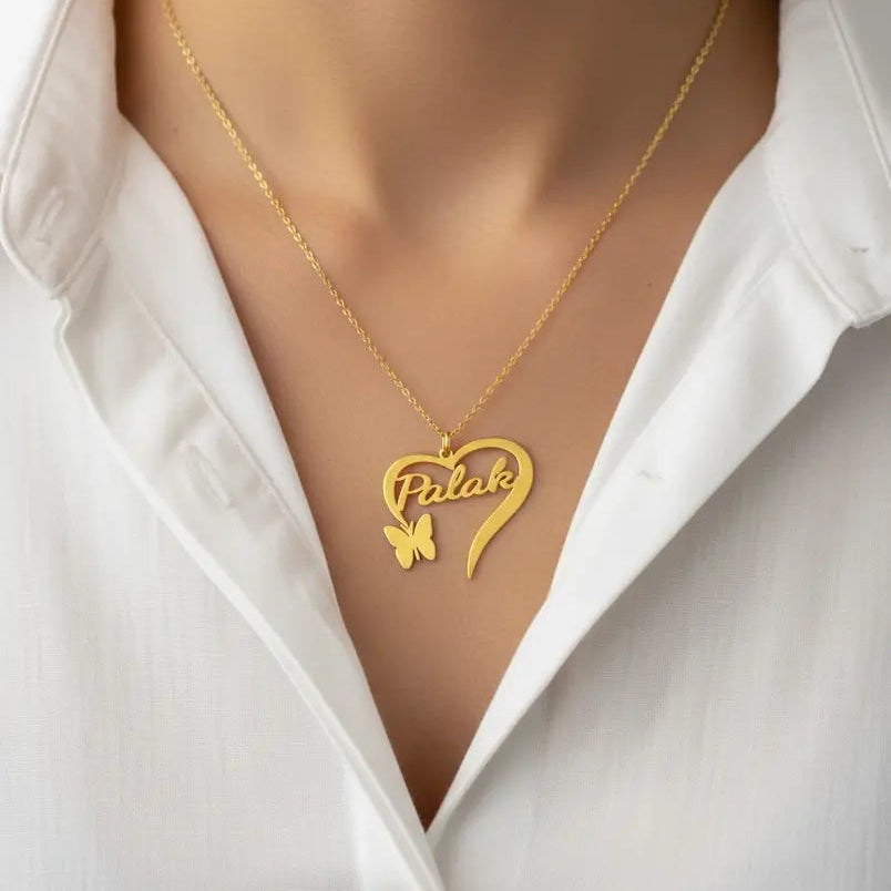 Gold necklace with a heart-shaped pendant and butterfly design on a mannequin wearing a white shirt.