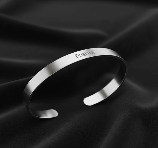Silver bracelet with 'Rahul' engraving on a dark fabric background