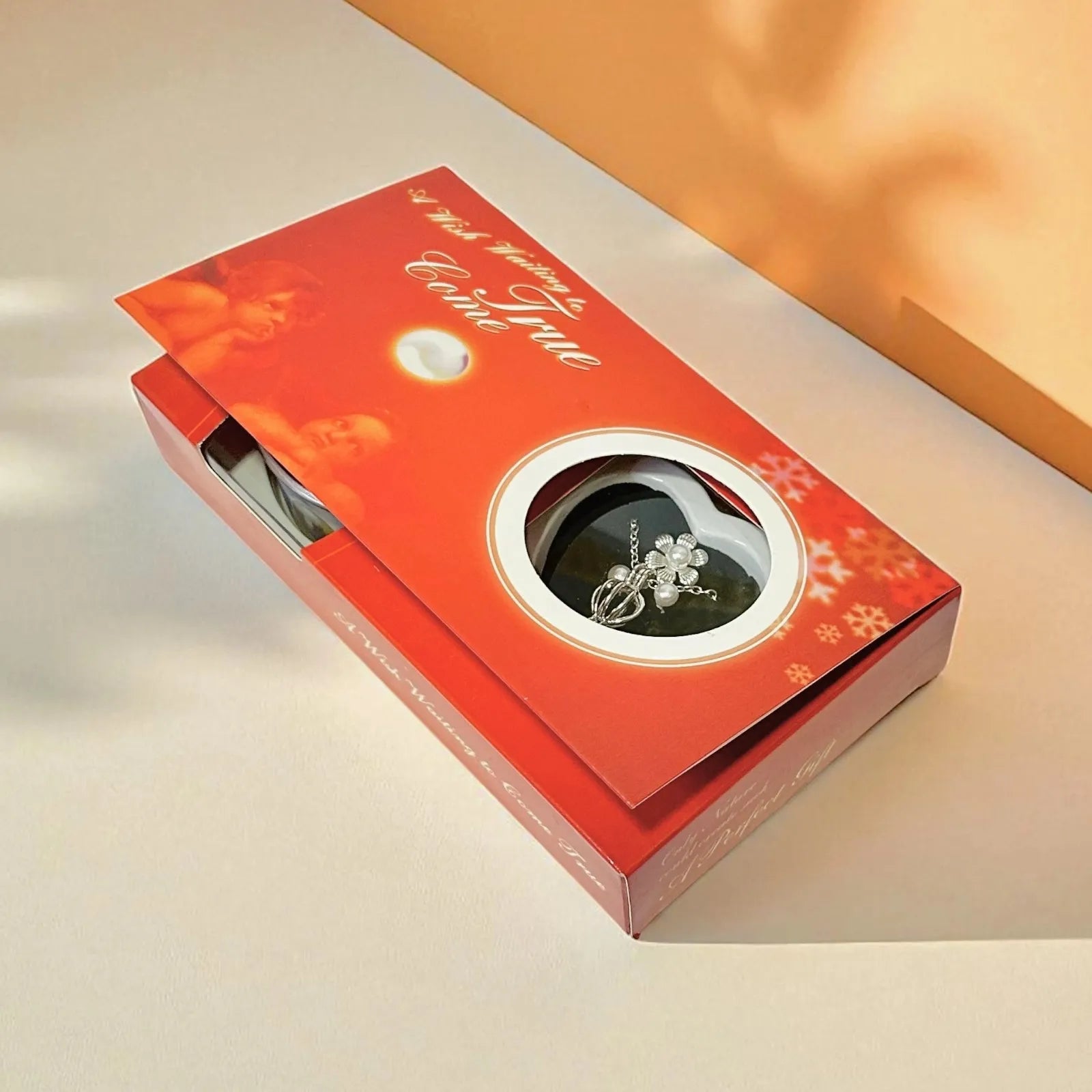 Red jewelry box with a silver ring inside on a beige surface